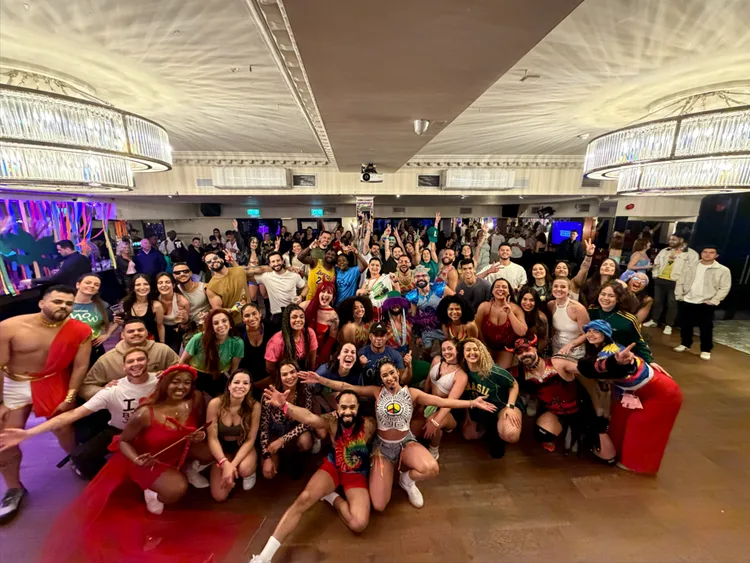 A big crowd of dancers in colourful costumes posing together at a Brazil FitDance party